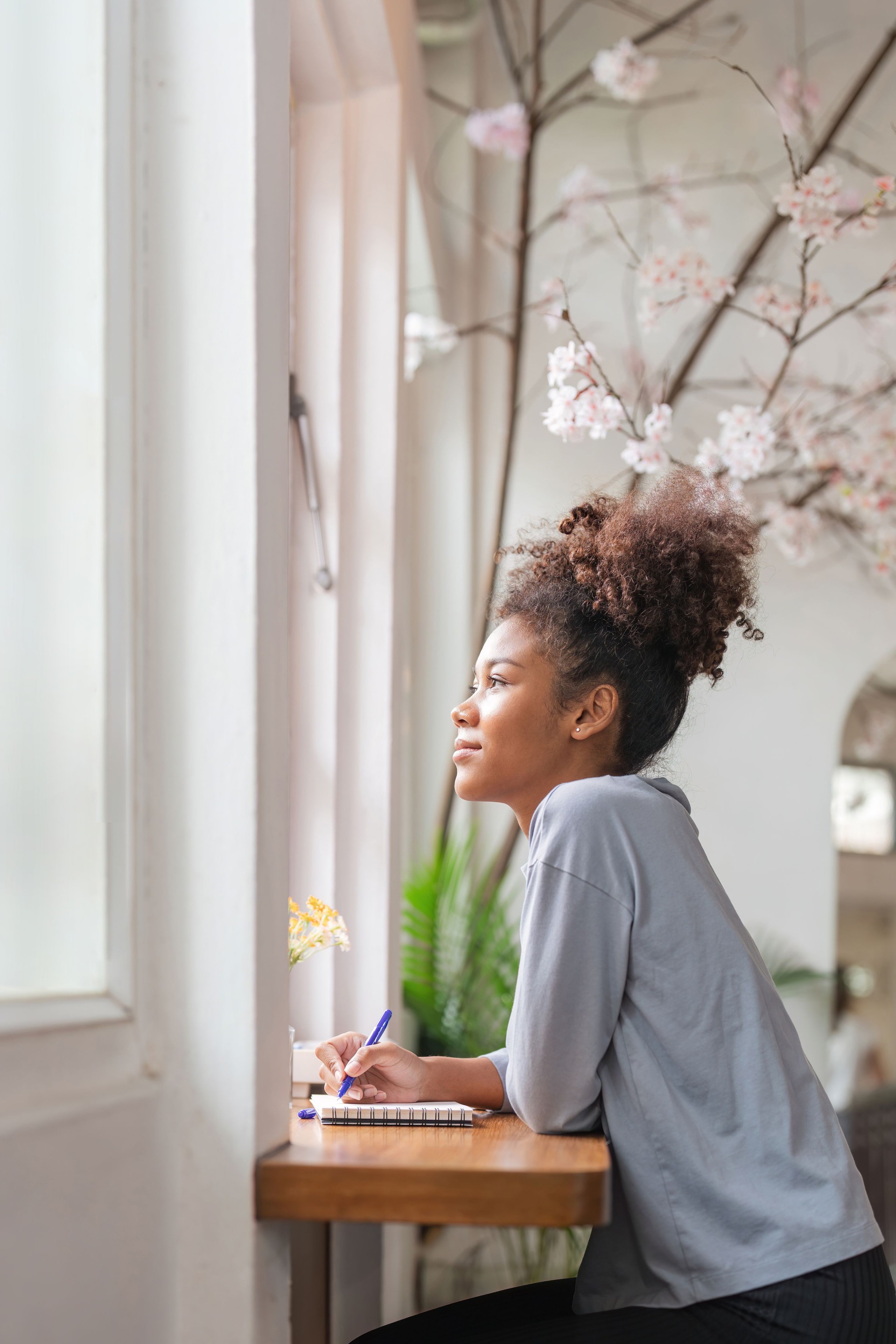 Young African American woman sit on comfortable desk in living room and write down in diary